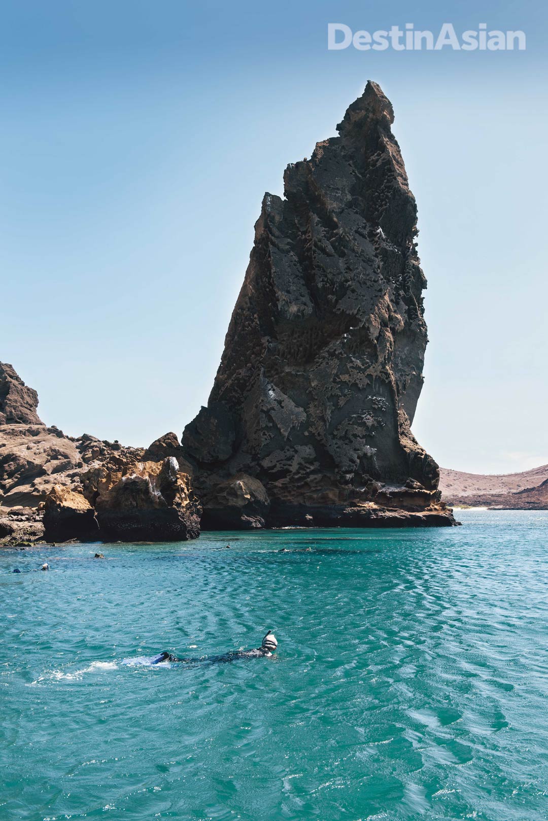 Snorkelers braving the cold waters off Bartolomé Island's iconic Pinnacle Rock.