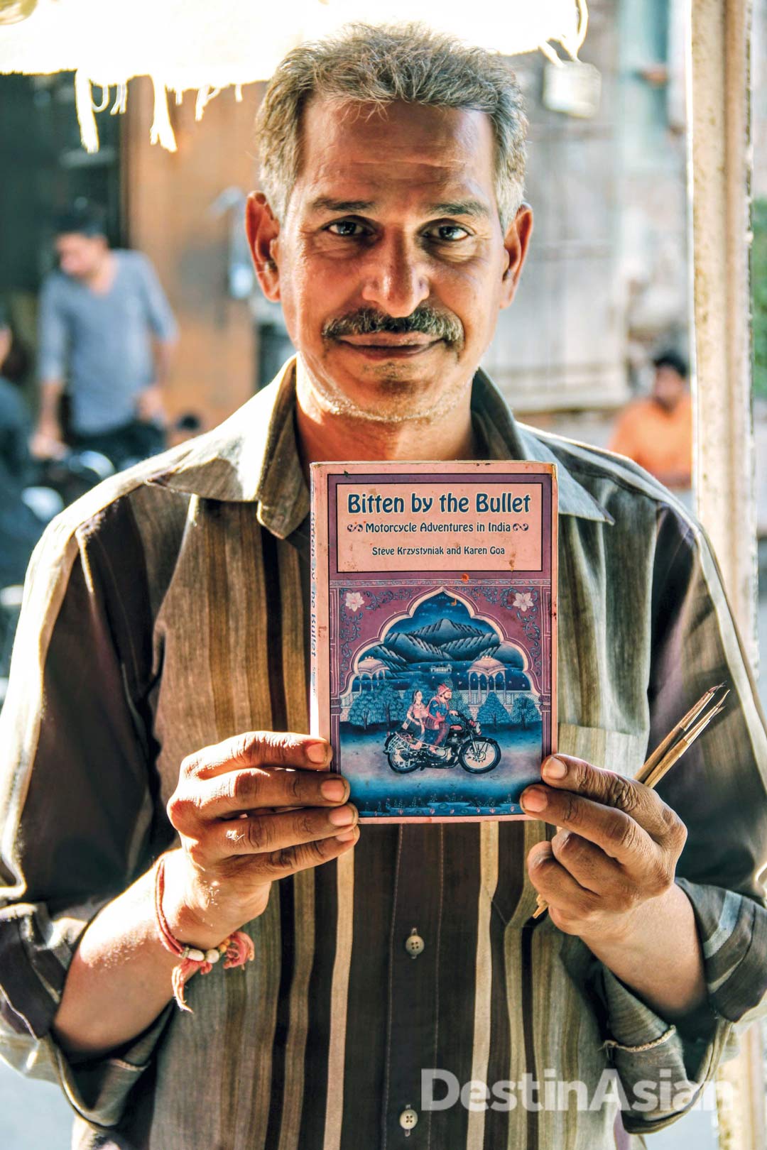 A local artist on Bundi's main street proudly brandishing a foreign book cover he was commissioned to design.