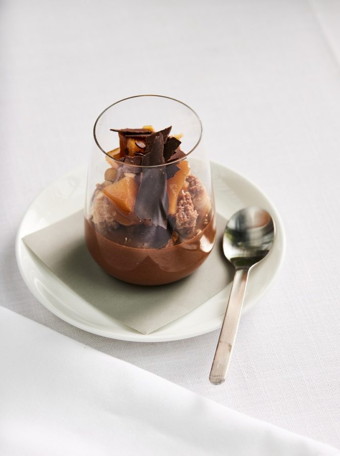 Dark chocolate cream with hazelnut cake, caramel pear, and chocolate pearls, served in Qantas first and international business class.